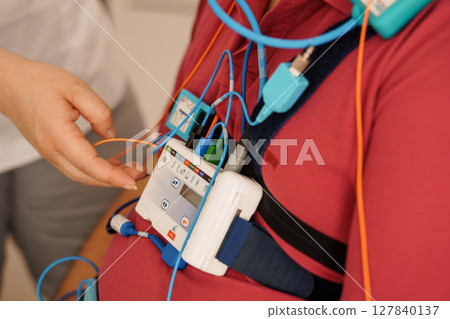 Stationary Polysomnography System Monitoring Patient Chest with Sensors and Wires, Diagnostic Healthcare Device, Light Blue and Red Tones. Stationary Polysomnography System Monitoring Patient Chest with Sensors and Wires, Diagnostic Healthcare Device, Light Blue and Red Tones. 127840137