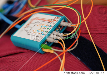 Polysomnography System Recording Setup with Multicolored Wires on Pink Fabric Background, Medical Diagnostic Device, EEG Monitoring, Healthcare Technology 127840144