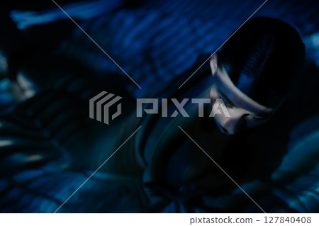 Woman illuminated by projector light creating artistic shadows indoors Woman illuminated by projector light creating artistic shadows indoors 127840408