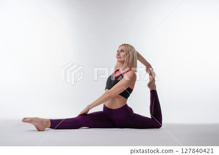 Woman practicing advanced yoga split pose in a bright studio setting 127840421