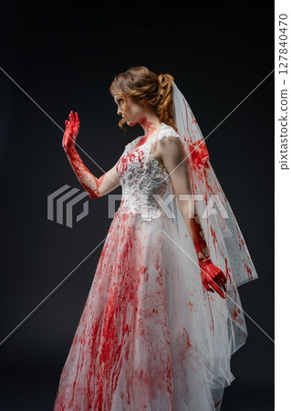 Bride in blood-stained lingerie holds katana in a dark, dramatic setting 127840470