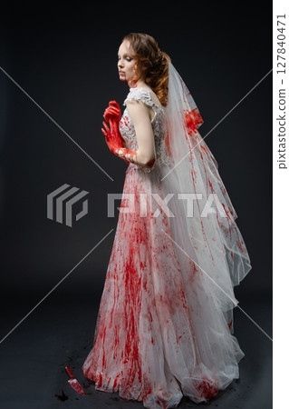 Bride in bloodstained gown holding katana in dramatic pose 127840471