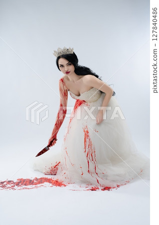 Dramatic portrayal of a bride with a knife and vivid blood splatter 127840486