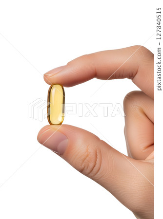 Hand holding omega-3 fish oil capsule isolated on transparent background, supplement close-up 127840515