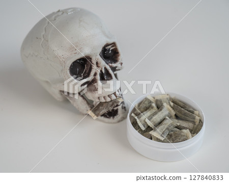 Skull Chewing Tobacco on a White Table. 127840833