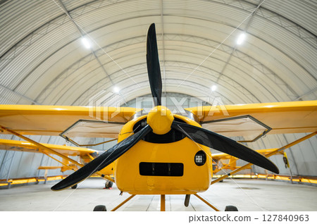 Yellow airplane glider in the hangar.  127840963