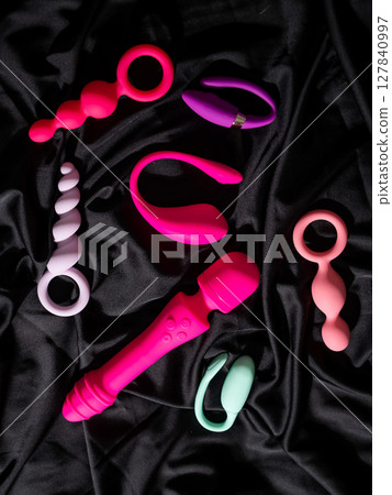 Collection of sex toys on a black sheet. Top view of various vibrators.  127840997
