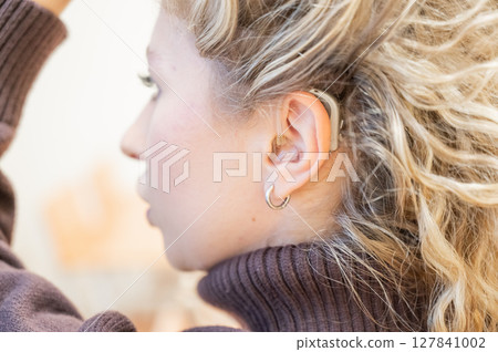 Close-up of a hearing aid on the ear of a young Caucasian woman. Close-up of a hearing aid on the ear of a young Caucasian woman. 127841002