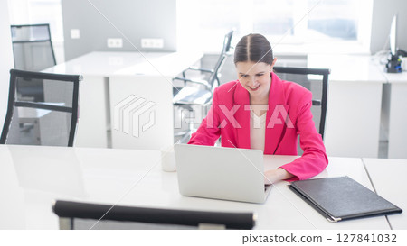 Caucasian business woman in fuchsia jacket working at computer.  127841032