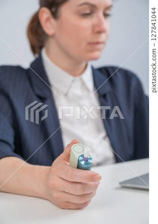 Business woman smoking an electronic cigarette while working on a laptop. Tobacco heating system. Business woman smoking an electronic cigarette while working on a laptop. Tobacco heating system. 127841044