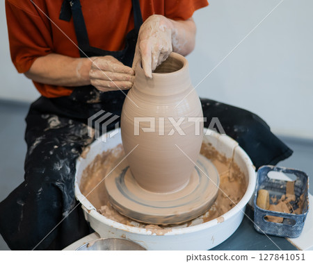 Close-up of a potter's hands making a ceramic vase on a potter's wheel. Close-up of a potter's hands making a ceramic vase on a potter's wheel. 127841051