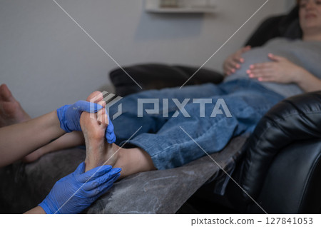 Pregnant woman getting professional foot massage. 127841053