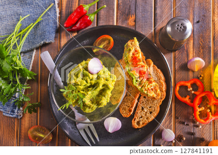 Traditional Mexican Dip Sauce Guacamole in a bowl with bread toasts Traditional Mexican Dip Sauce Guacamole in a bowl with bread toasts 127841191