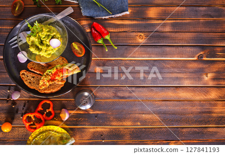 Traditional Mexican Dip Sauce Guacamole in a bowl with bread toasts 127841193
