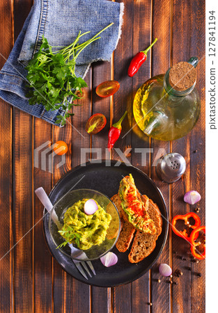 Traditional Mexican Dip Sauce Guacamole in a bowl with bread toasts Traditional Mexican Dip Sauce Guacamole in a bowl with bread toasts 127841194