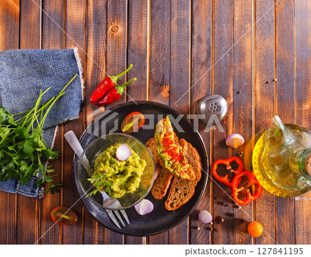 Traditional Mexican Dip Sauce Guacamole in a bowl with bread toasts Traditional Mexican Dip Sauce Guacamole in a bowl with bread toasts 127841195
