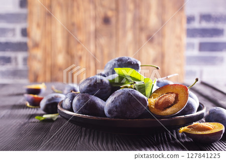 Ripe plum on dark wooden background 127841225