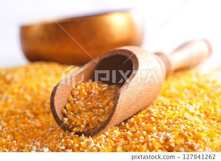 Millet in a bowl and spoon with twigs on a table. 127841262