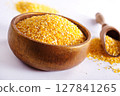 Millet in a bowl and spoon with twigs on a table. 127841265