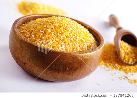 Millet in a bowl and spoon with twigs on a table. 127841265