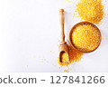 Millet in a bowl and spoon with twigs on a table. 127841266