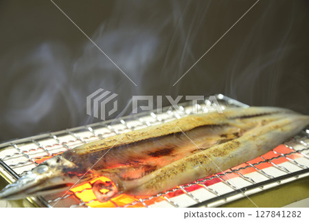 在炭火上烤秋刀魚片，煙霧繚繞 127841282