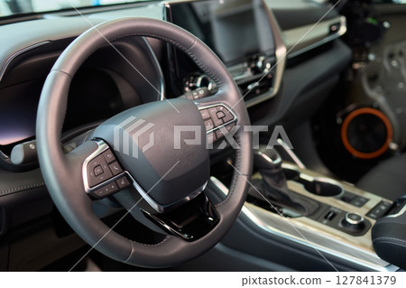 Closeup of a modern car steering wheel with control buttons for technology and convenience Closeup of a modern car steering wheel with control buttons for technology and convenience 127841379