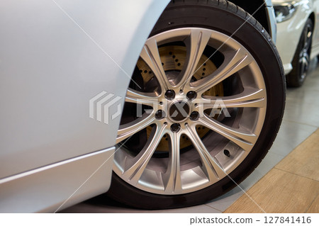 Detailed shot of a sleek black and silver alloy wheel on a motor vehicle 127841416