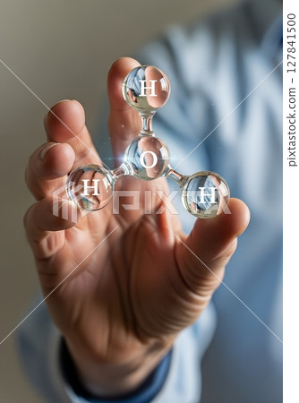 Close-up of hand holding transparent molecule model, hydrogen and oxygen atoms 127841500