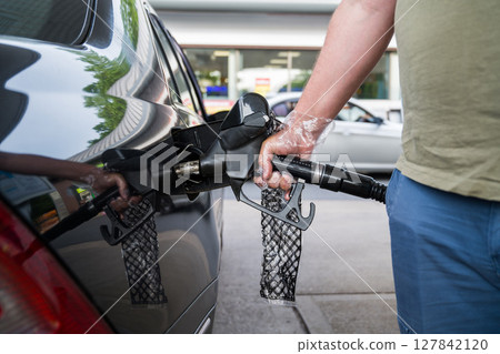 Man driver hand refilling the car with fuel at the gas petrol station. Man driver hand refilling the car with fuel at the gas petrol station. 127842120
