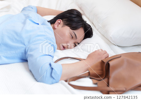 A man collapses into bed due to overwork 127842135