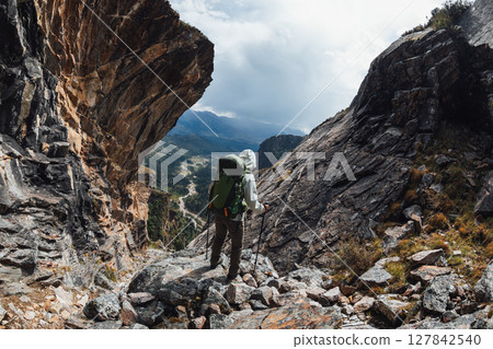 Backpacking woman climbing up on steep cliff edge at high altitude mountains top Backpacking woman climbing up on steep cliff edge at high altitude mountains top 127842540