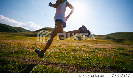 Fitness woman runner running at flowering grassland mountain top Fitness woman runner running at flowering grassland mountain top 127842547