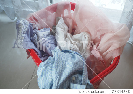 Colorful laundry in a red basket by a window brightens the space 127844288