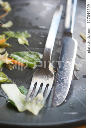 An empty dirty plate with a fork. 127844309
