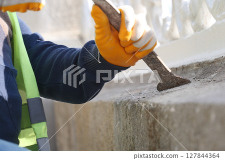 A dedicated worker meticulously restoring a wall using various tools A dedicated worker meticulously restoring a wall using various tools 127844364