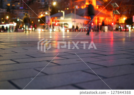 Captivating and Vibrant Reflections on Wet Pavement Under the Night Sky 127844388