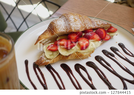 A Delicious Croissant Filled Generously with Fresh Strawberries and Bananas 127844415