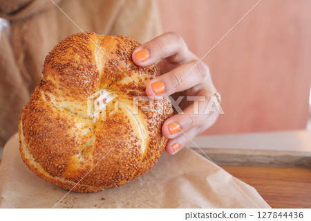 A Freshly Baked Bagel That Is Decorated With Colorful Nail Polish on Hand 127844436
