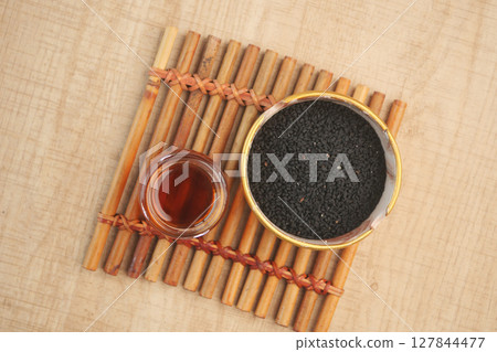 Black Seeds and Their Oil Beautifully Arranged in a Rustic Wooden Bowl for Culinary Uses Black Seeds and Their Oil Beautifully Arranged in a Rustic Wooden Bowl for Culinary Uses 127844477