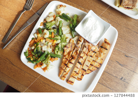 Delicious Grilled Chicken Paired with Fresh Vegetables and a Creamy Yogurt Sauce 127844488