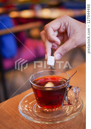 A Sugar Cube Delicately Being Added to a Warm Cup of Coffee, Enhancing the Experience A Sugar Cube Delicately Being Added to a Warm Cup of Coffee, Enhancing the Experience 127844498