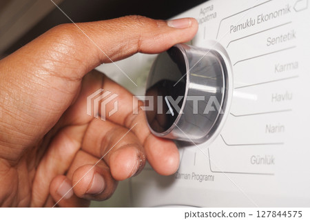 Adjusting the settings on a washing machine at home Adjusting the settings on a washing machine at home 127844575