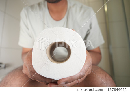 Person holding toilet paper in a bathroom setting 127844611