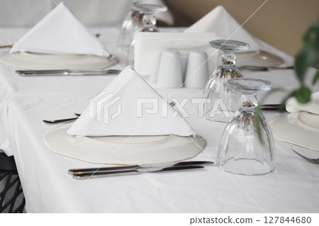 Elegant dining setup with folded napkins and glassware Elegant dining setup with folded napkins and glassware 127844680