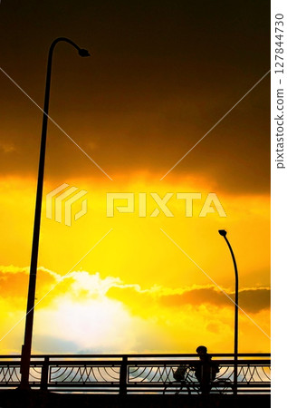 A bicycle riding on an overpass while looking up at the clouds floating in the sunset sky A bicycle riding on an overpass while looking up at the clouds floating in the sunset sky 127844730