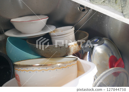 Dishes piling up in a kitchen sink after a meal Dishes piling up in a kitchen sink after a meal 127844738