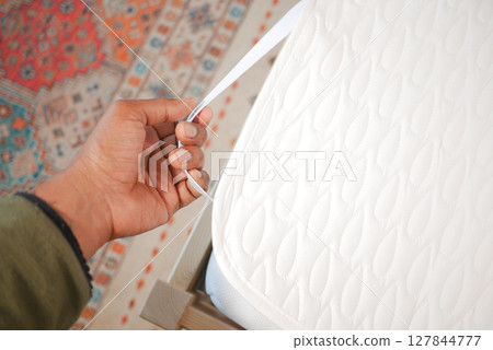 Person adjusting mattress protector on a bed Person adjusting mattress protector on a bed 127844777