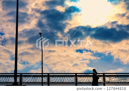 Woman crossing an overpass with a cloudy sky Woman crossing an overpass with a cloudy sky 127844818