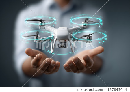 Drone hovering above open hands, showcasing advanced technology with holographic elements, symbolizing innovation and precision aerial operations 127845044
